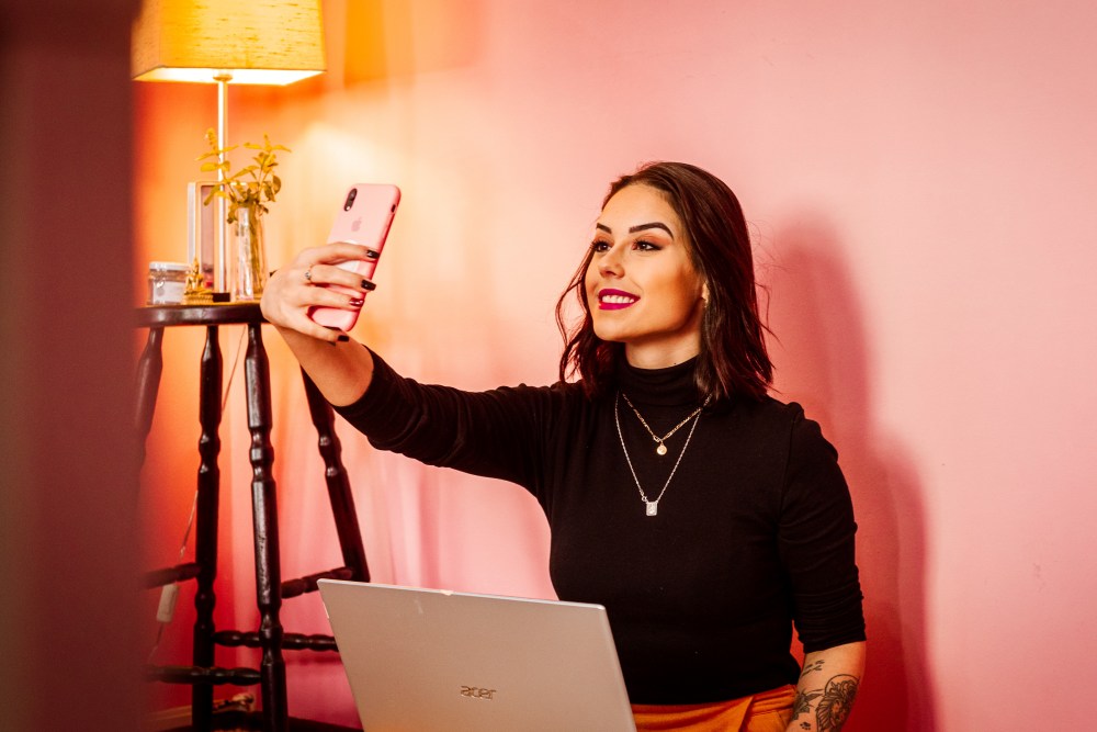 Influencer taking selfie with pink background