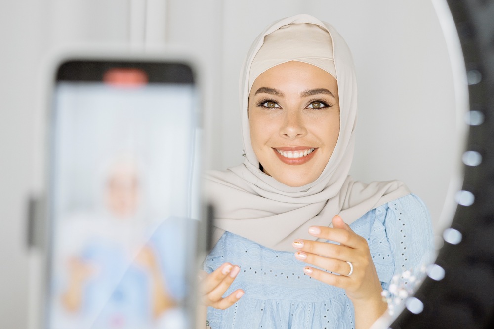 Woman in hijab recoding social media content on phone