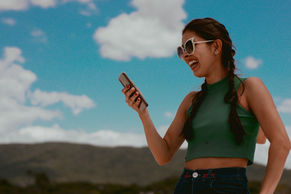 Girl laughing at phone outdoors
